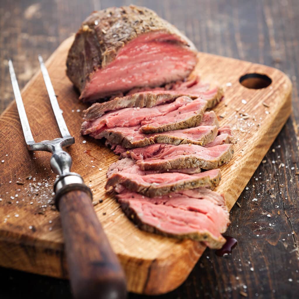 roast beef on cutting board and meat fork